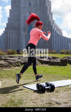 Reykjavík, Islanda. 25/05/2018 Meteo. Pomeriggio di sole nella capitale come Hannah Eden (Eden fitness training online) esegue una routine per un esercizio video, di fronte alla chiesa Hallgrímskirkja che è Reykjavik il punto di riferimento principale. Foto Stock
