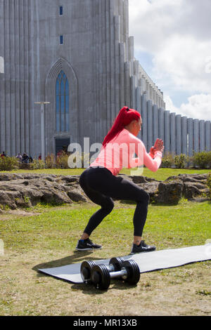 Reykjavík, Islanda. 25/05/2018 Meteo. Pomeriggio di sole nella capitale come Hannah Eden (Eden fitness training online) esegue una routine per un esercizio video, di fronte alla chiesa Hallgrímskirkja che è Reykjavik il punto di riferimento principale. Foto Stock