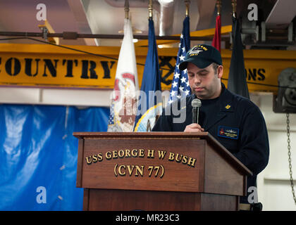 170501-N-JC445-016 GOLFO ARABICO (1 maggio 2017) Chief Warrant Officer Kevin McCreevan parla come maestro di cerimonie durante una cerimonia di messa in funzione in fo'c'sle della portaerei USS George H.W. Bussola (CVN 77) (GHWB). GHWB è distribuito negli Stati Uniti Quinta Flotta area di operazioni a sostegno della sicurezza marittima operazioni destinate a rassicurare gli alleati e partner e preservare la libertà di navigazione e il libero flusso di commercio nella regione. (U.S. Foto di Marina di Massa lo specialista di comunicazione di terza classe Mario Coto/rilasciato) Foto Stock