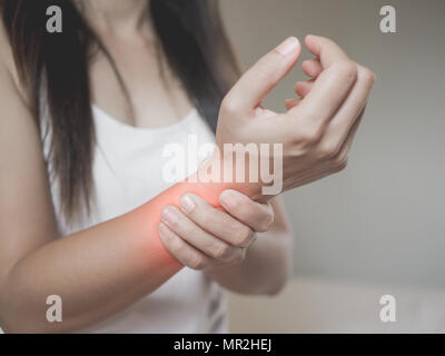 Closeup donna trattiene la sua mano da polso pregiudizio, sensazione di dolore. Medico e sanitario conept. Foto Stock