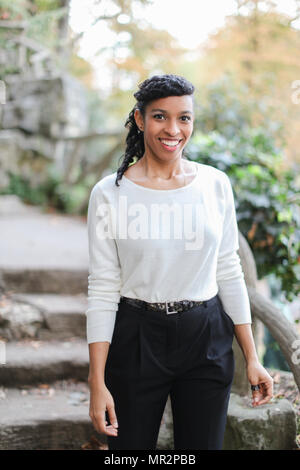 Nero ragazza carina che indossa camicia bianca e pantaloni in scale di pietra dello sfondo. Concetto di eleganza Afro American persona e bellezza naturale. Foto Stock