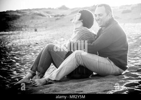 Carino l uomo e la donna sono di mezza età divertendosi in amore in spiaggia all'aperto. Le attività per il tempo libero e un grande sorriso e ridere per la signora. l'uomo abbracciare il suo. ro Foto Stock