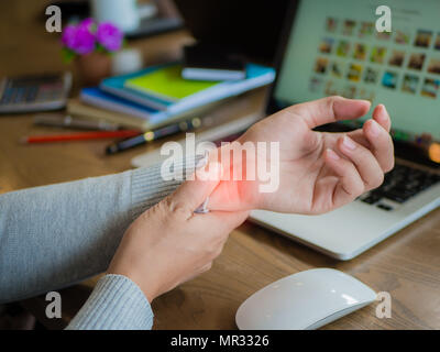 Closeup donna che mantiene il suo dolore al polso dall'utilizzo del computer lungo tempo. Ufficio concetto di sindrome. Foto Stock