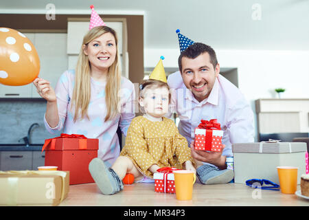 Una famiglia con una torta si congratula con un bambino felice per il suo compleanno Foto Stock