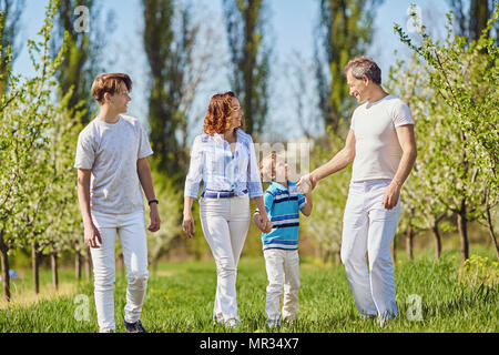 Una famiglia felice passeggiate nel giardino in primavera e in estate. Foto Stock