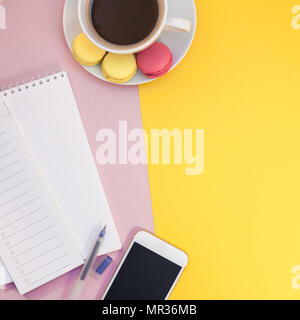 Creative quadrato piatto foto laici della tazza di caffè con amaretti e un blocco note con copia spazio sul rosa e sfondo giallo stile minimal Foto Stock