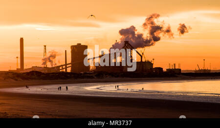 Tramonto fotografia scattata a Redcar, guardando indietro lungo la costa verso la Corus impianto siderurgico con figure sulla spiaggia Foto Stock