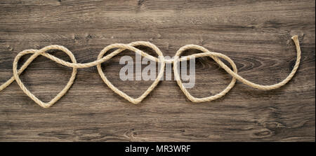 Cuore di tre forme di corda sul legno vecchio Foto Stock