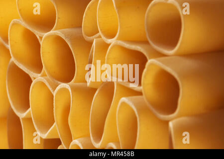 Pila di pasta paccheri-schiaffoni-close up tradizionale pasta italiana ,la retroilluminazione e la diagonale crea un effetto grafico ,messa a fuoco morbida Foto Stock