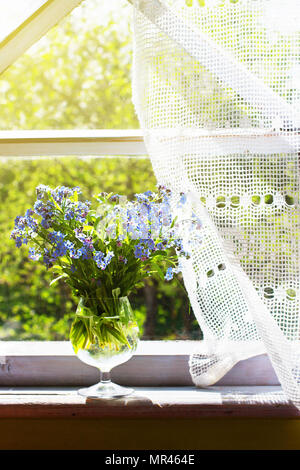 Bouquet di fresca di dimenticare me not (Myosotis arvense) nella Wineglass sul davanzale della finestra nella vecchia casa rustica Foto Stock