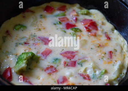 Frittata di cottura in una padella, pronti a servire. Con pomodoro e cipolla rossa, formaggio di capra e prezzemolo Foto Stock