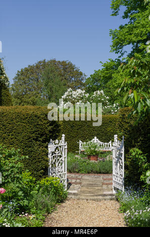 Bianco aperto porte che conduce nel giardino formale con un sedile bianco opposto; parte di Kathy Brown's Garden, Stevington, Bedfordshire, Regno Unito Foto Stock