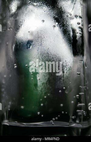 La texture di gocce di acqua in un bicchiere di acqua che guarda come blocco di ghiaccio. Verde bottiglia risulta sfocato in background Foto Stock