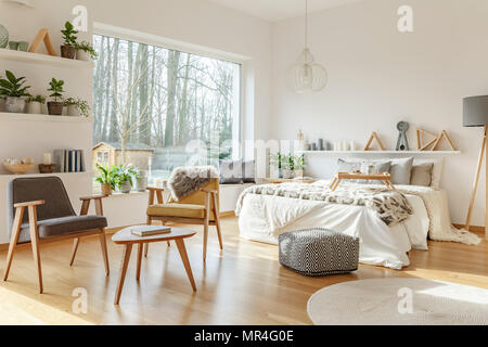 Grigio e giallo poltroncina in legno in spazio aperto interno con letto matrimoniale e vista sulla foresta Foto Stock