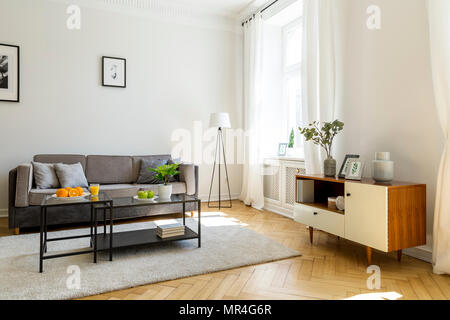 Foto reale di un divano grigio bianco e nero con cuscini in un salotto  interno con pavimento a scacchi e poster in oro dei fotogrammi su una parete  Foto stock - Alamy