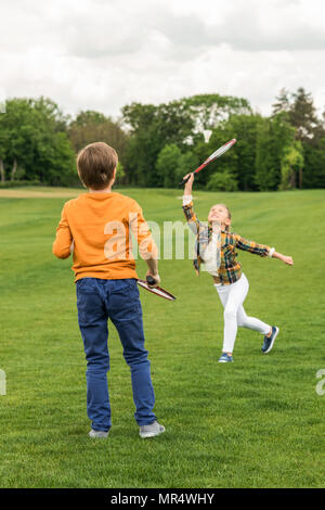 Carino il fratello e sorella e riproduzione di badminton su erba verde Foto Stock