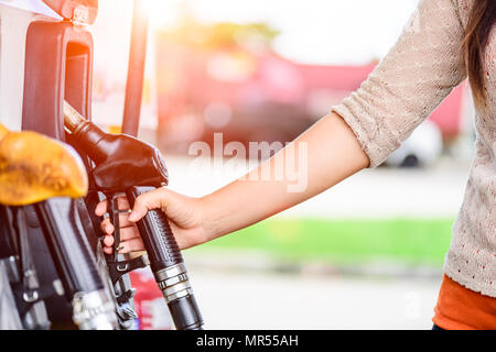 Primo piano della donna mano che tiene una pompa di carburante in una stazione. Foto Stock