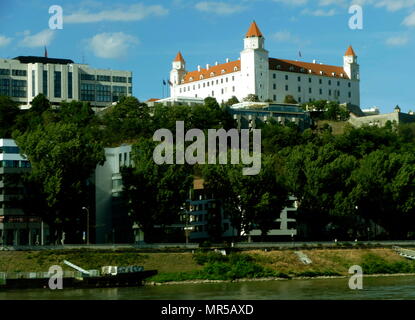 Fotografia di presa degli edifici lungo il corso del fiume Danubio a Bratislava, la capitale della Slovacchia. Il rosso coperto e il castello di Bratislava è visibile. Il castello risale al XIII secolo e ospita il parlamento slovacco. Xxi secolo Foto Stock