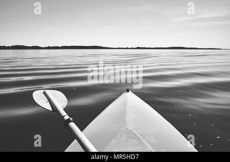 Retrò immagine stilizzata di un archetto di un kayak con paddle su un lago, il fuoco selettivo. Foto Stock