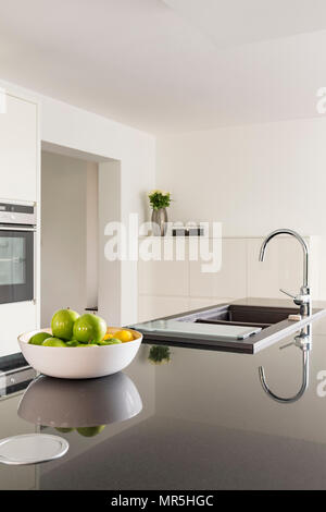 Cucina bianca con piano di lavoro nero e lavabo Foto Stock
