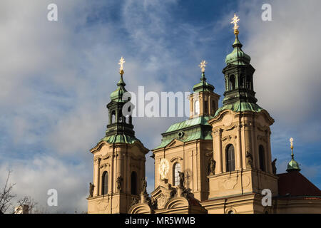 Torri di San Nicolaus chiesa a Praga, Repubblica Ceca. Facciata colorata dalla luce solare in golden, insieme con le croci alla fine delle torri. C Foto Stock