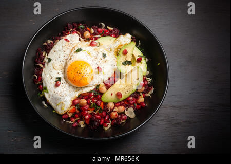 Miso veggie colazione ciotola fatta con barbabietole, carote, i cavoli di Bruxelles, kale, ceci e guarnita con i semi di melograno, avocado e uova. Foto Stock