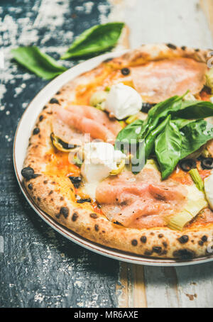 Italiano per pranzo o cena. Pane appena sfornato la pizza con carciofi, tacchino affumicato Prosciutto, olive, crema di formaggio e le foglie di basilico su legno rustico sfondo, Foto Stock