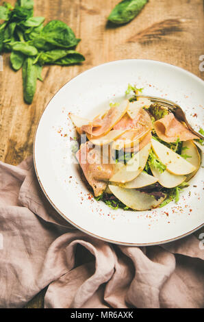 Fresca Insalata estiva con tacchino affumicato Prosciutto e pera in piastra bianca su tavola in legno rustico sfondo Foto Stock