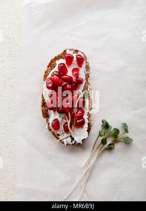 Bruschetta con i semi di melograno e crema di formaggio con microgreens Foto Stock