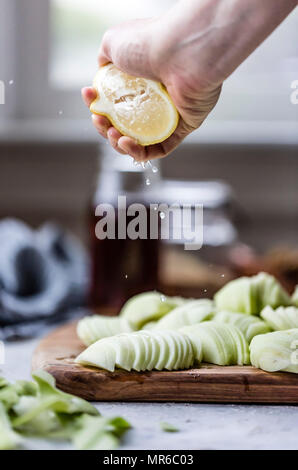 Spremendo il succo di limone fresco su mele sbucciate Foto Stock