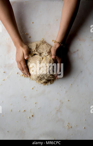 Mani rendendo la pasta a torta su marmo Foto Stock