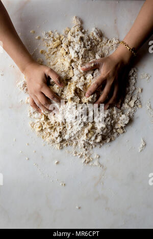 Mani rendendo la pasta a torta su marmo Foto Stock