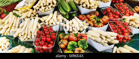 Pressione di stallo di mercato con molla fresche verdure di stagione a strada parigina farmers market. Asparagi bianchi, pomodori e cetrioli. Foto Stock