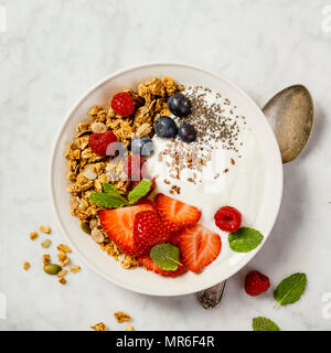 Ciotola di muesli fatti in casa con yogurt e frutti di bosco freschi su  marmo bianco dello sfondo. Vista superiore, piatto laici. Colazione sana  nozione. Spazio per il testo Foto stock 