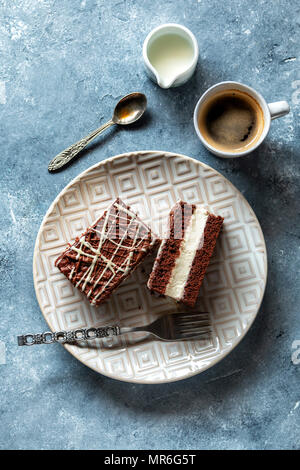 Torta al cioccolato farciti di crema sulla piastra e una tazza di caffè sul tavolo Foto Stock