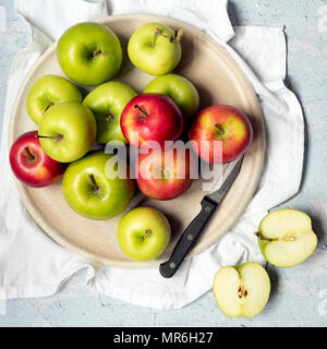 Il rosso e il verde di mele con un coltello e due metà di Apple su una tavola di legno che serve board. Foto Stock