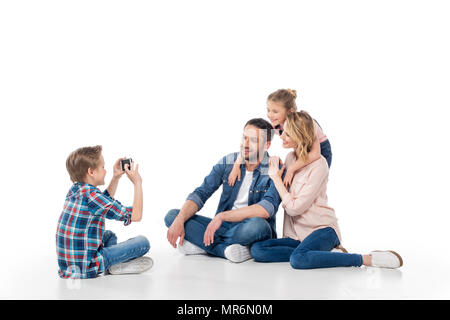 Little Boy prendendo foto sulla sua famiglia sullo smartphone, isolato su bianco Foto Stock