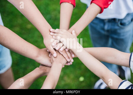 Ritagliato colpo di impilamento dei bambini le mani e piedi su erba verde Foto Stock