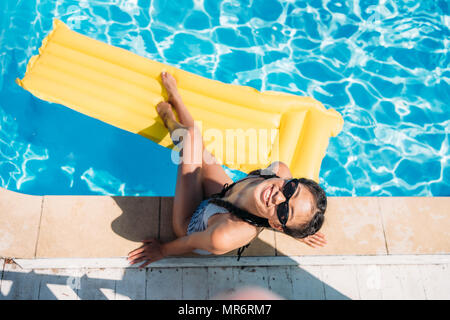 Vista superiore donna asiatica in appoggio vicino alla piscina presso il resort Foto Stock