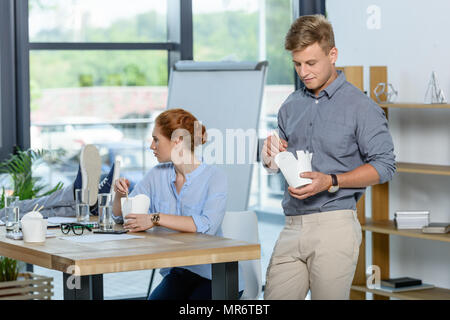 Il team Aziende a mangiare cibo cinese durante la pausa riunione in ufficio moderno Foto Stock