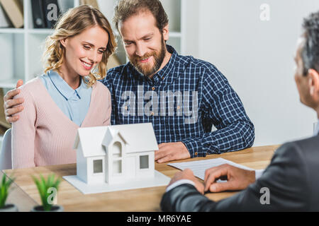 Ritratto di giovane avente incontro con agente immobiliare in agenzia immobiliare office Foto Stock