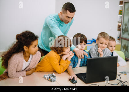 I bambini lavorano con docente sulla classe di programmazione Foto Stock