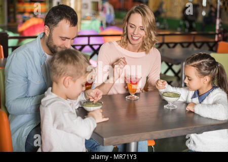 La famiglia felice di mangiare dolci insieme al cafe Foto Stock