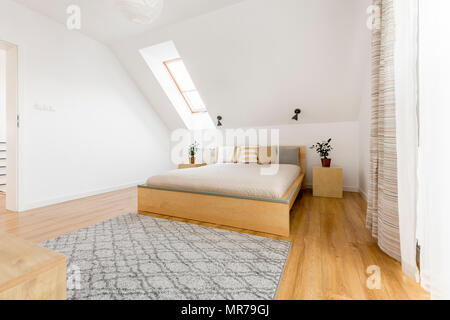 Camera mansardata con finestra, letto in legno e pannelli di pavimento Foto Stock
