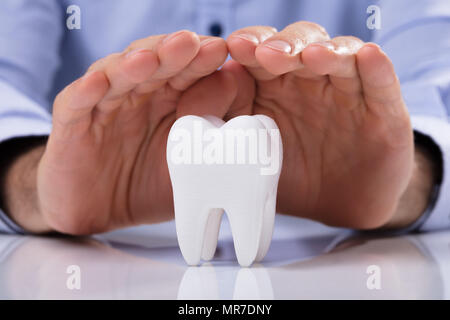 Mano d'uomo proteggere igienicamente sano Dente Bianco sul tavolo riflettente Foto Stock