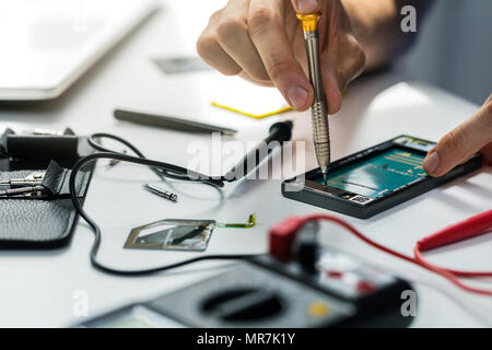 Il tecnico di riparazione telefono rotto Foto Stock