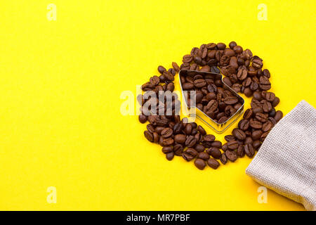 I chicchi di caffè in forma di freccia su sfondo giallo Foto Stock