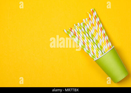 Cocktail variopinti tubi nel libro verde tazza monouso su sfondo giallo Foto Stock