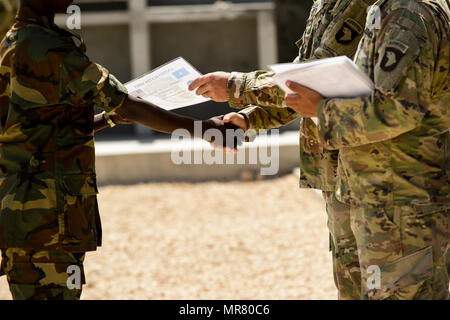 I soldati della U.S. Dell'esercito 101ª Divisione aviotrasportata presente certificati di formazione a completamento nazionali somale soldati dell esercito durante una cerimonia di consegna dei diplomi il 24 maggio 2017, a Mogadiscio in Somalia. Il corso di sei settimane incentrati su vari aspetti di spostamento di personale, attrezzature e forniture. (U.S. Air Force photo by Staff Sgt. Nicola M. Byers) Foto Stock