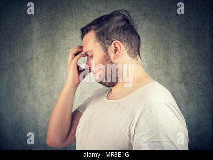 Vista laterale del giovane uomo sovrappeso pensando alla soluzione durante lo sfregamento sulla fronte. Foto Stock